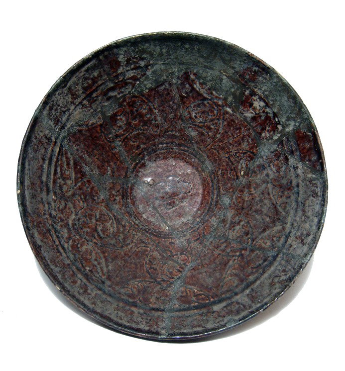 Iranian purple-glazed bowl, incised decoration: An Iranian purple-glazed bowl with incised decoration, c. 10th - 11th Century AD, consisting of floral devices and concentric circles. Some repair and restoration. H: 2 7/8" (7.3 cm); Dia: 7 3/4" (19.