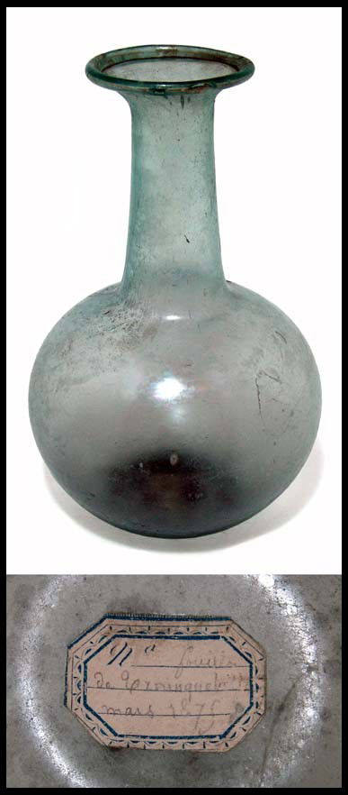 Roman green glass bottle found in March, 1875: A large pale green glass bottle, Roman, 3rd - 4th Century AD, with thin walls and concave base, long tubular neck with the rim folded in. Intact and a choice example! H: 7" (18 cm). Cf. Yale, p. 78, n
