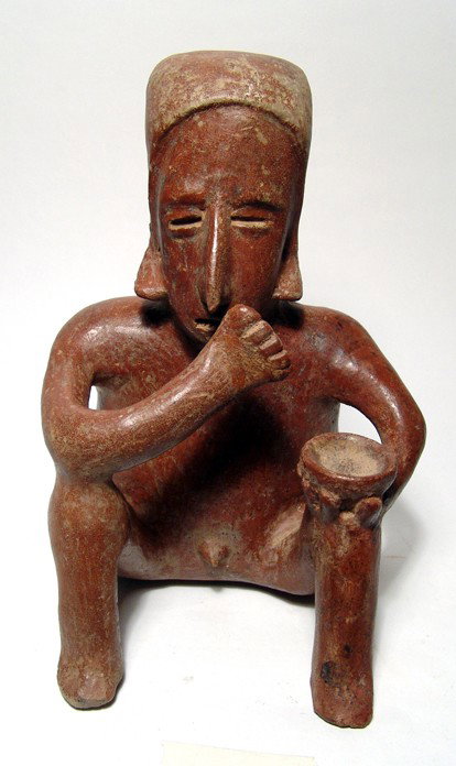 Choice Jalisco red-ware seated male figure: A choice Jalisco red-ware seated male figure. West Mexico, c. 200 BC - AD 350. A well preserved figure, seated on the ground, left hand holding a bowl on his knee, right hand to mouth. His head is sle