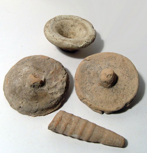 A group of 4 ancient terracotta objects: A group of 4 terracotta objects. Lot includes a small Graeco-Roman votive dish, a pair of stylized Etruscan votive breasts, and the base of an amphora. Ex Dr. Gilles collection, Germany, acquired prio