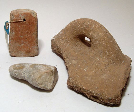 A lot of 3 mixed ancient items: A lot of 3 mixed items. Lot includes a large jar handle from a terracotta vessel, a Hellenistic terracotta loom weight with collection label giving the provenance as Byblos, Phoenicia, 1966, and a par