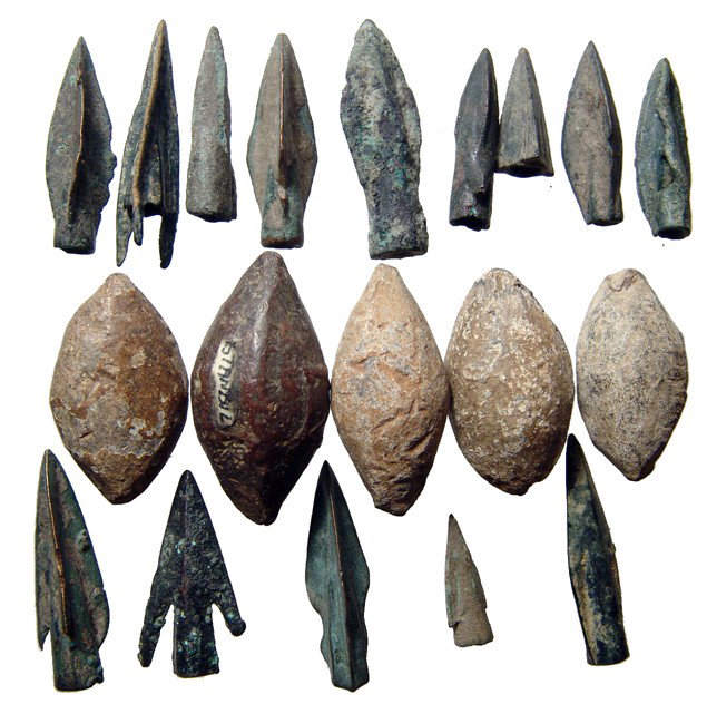 Roman sling stones and ancient arrow points: A group of Roman sling stones and ancient bronze arrow points. Lot includes 5 Roman lead sling stones, one with raised design, c. 1st Century BC/AD, largest 37mm in length. The 14 bronze arrow points 