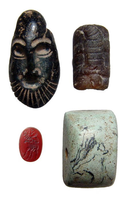 Lot of antique seals, intaglio and glass bead: A lot of 2 seals, and intaglio and a glass bead, all early - mid 20th Century. Lot includes a black steatite seal in the form of a bearded male head, a winged creature on the backside, suspension loop