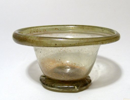 Roman olive-green glass bowl: A Roman olive-green glass bowl, 3rd - 4th Century AD, the splayed foot with thick unground pontil mark, deep body with flared shoulder, the 'collar-type' vertical rim folded back on itself. H: 2 1/8" 