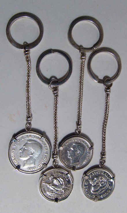 4 silver keychains with Australian silver coins: A lot of 4 silver key chains, each with an Australian silver coin. Lot includes three key chains containing a silver shilling, dates - 1946, 1952 & 1955, and one with a silver florin from 1946. Each c
