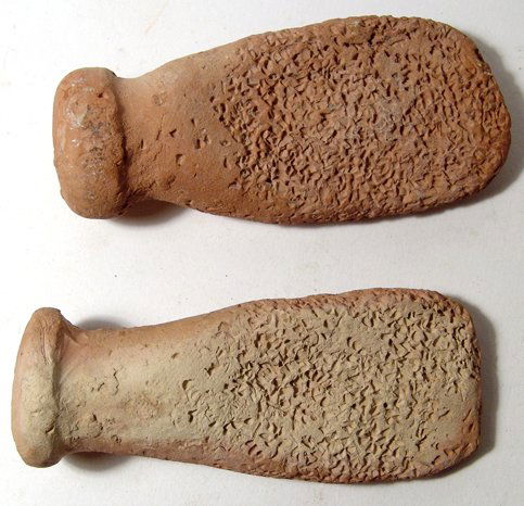 2 Near Eastern terracotta graters or fish scalers: A pair of terracotta graters or fish scalers, Near Eastern, 7th - 12th Century, each side flattened and roughened, the handles rolled with a lightly indented end. Both about 5" (12.8 cm). Intact. Ex N