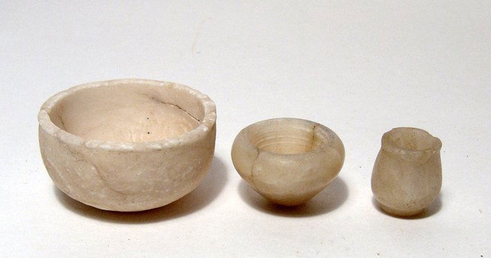 Lot of 3 small Egyptian alabaster vessels: A lot of 3 small Egyptian alabaster vessels. Lot includes a pair of Old Kingdom bowls and a small New Kingdom jar. Largest: H: 1 1/8" (1.9 cm); Dia: 2 1/4" (5.7 cm). Largest with some age cracks. Ex o