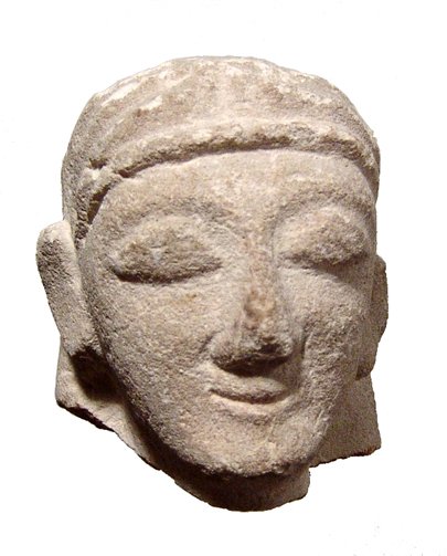 Cypriot limestone head of Kore: A Cypriot limestone head of Kore, c. 7th - 6th Century BC, wearing a layered headdress, his features placid with large eyes and pursed lips. H: 2 1/8" (5.4 cm). Ex New Jersey private collection.