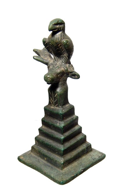 Roman bronze votive of an eagle: A Roman bronze votive of an eagle, c. 2nd - 3rd Century AD, standing upon the head of a stag, which in turn rests upon a tall stepped base. The figure is nicely detailed, the wings crossed behind. H: 