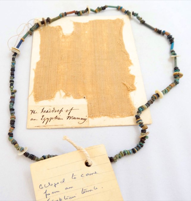 Egyptian "mummy linen" fragment and necklace: An Egyptian "mummy wrapping" linen fragment and faience-bead necklace, beads dating to the Late Period, c. 664-323 BC. 11.6 x 9.5 cm. Ex English private collection.