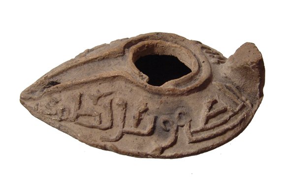 Early Islamic ceramic lamp with inscription: An early Islamic ceramic lamp with inscription, c. 7th - 8th Century AD. The lamp is mouldmade with sharp carination, the shoulders angled and decorated with an Islamic religious inscription. The fill
