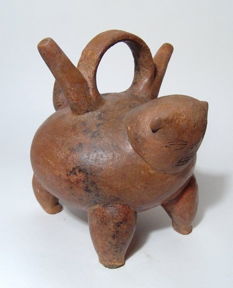 A Calima Feline Alcarraza Vessel from Colombia: A Calima feline Alcarraza vessel, Colombia, c. AD 1500, the body rounded with four legs, the head is stocky with incised features, the tail wide and pointed. On back, a large strap handle between a pa