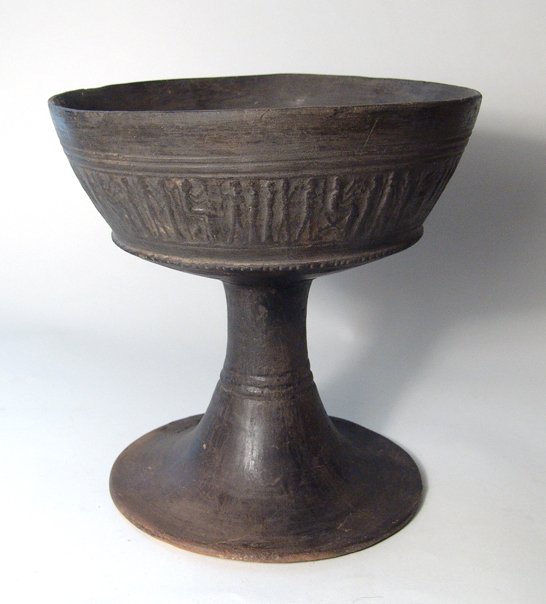 A highly detailed Etruscan Bucchero chalice: An Etruscan Bucchero chalice with cylinder impressed decoration, Italic, c. 600 - 550 BC, consisting of seated figures and with worshippers behind and before them. The central bowl surrounded by groov