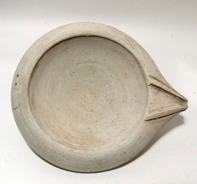 A Roman creme buff Mortarium: A Roman creme buff Mortarium, or mixing bowl, c. 2nd - 3rd Century AD, with rounded interior, sloping shoulder and a triangular spout. The vessel sits on a low ring foot and two hole in the back of th