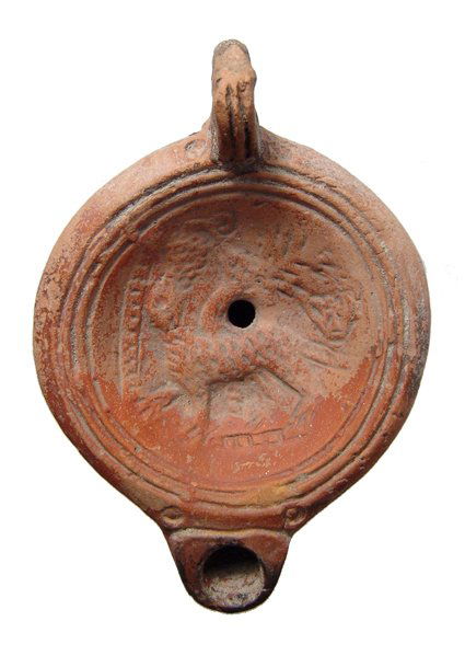 Roman ceramic lamp with a panther in discus: A Roman ceramic lamp with a panther in the discus, c. 2nd Century AD, the feline, representing Dionysos, looking skyward, tree before and a bunch of grapes and vine above, mask of kantharos behind. Th