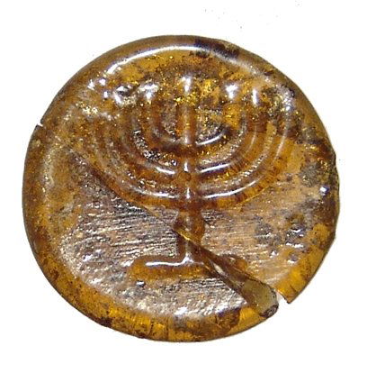 A Judaean glass counter with a menorah: A Judaean glass counter with a menorah, c. 5th - 7th Century AD, a deep orange-brown color with clear impression. Dia: 18mm. Repaired. Ex Los Angeles private collection.