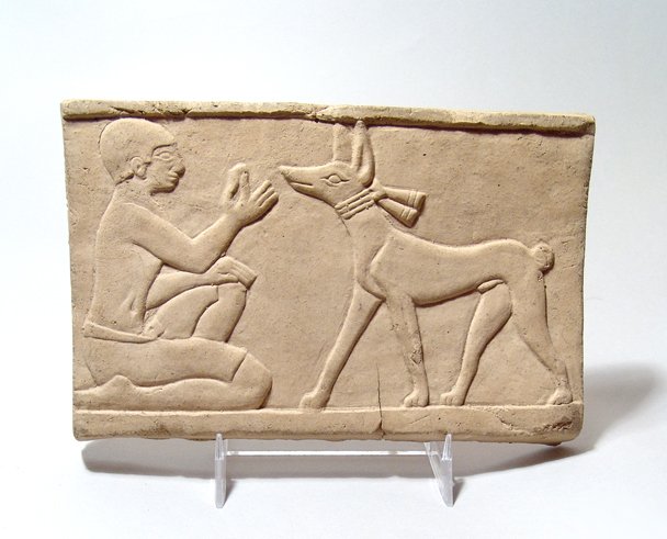 Egyptian Terracotta relief of Man Feeding Dog: Egyptian Terracotta relief of kneeling man feeding dog (Anubis), L: 18.6 cm, H: 11.9 cm. Ex Ohio private collection.