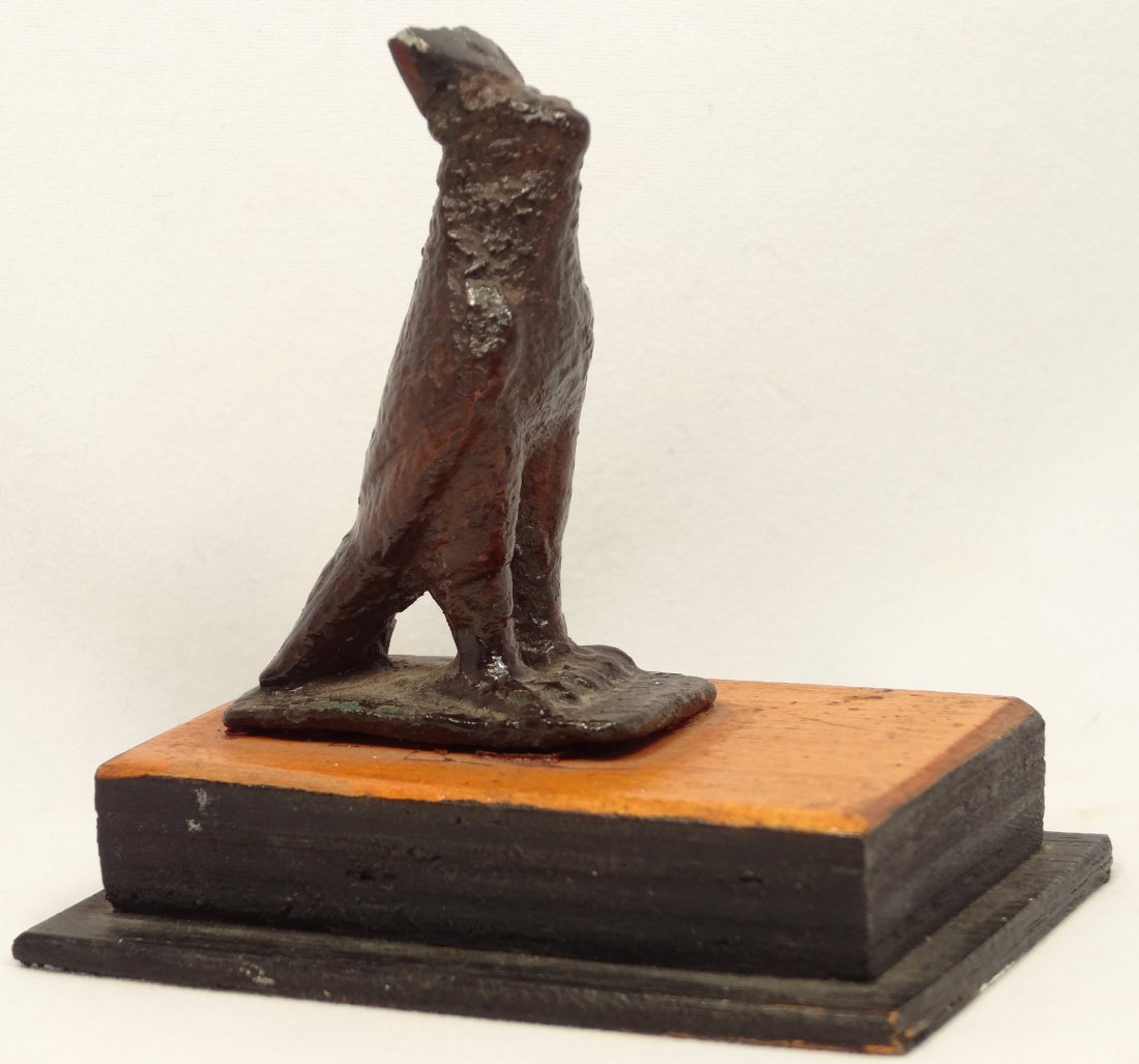 An Egyptian bronze votive figure of a Horus falcon: An Egyptian bronze votive figure of a Horus falcon, Late Period, c. 664 - 30 BC. With some loss to the headress and mounted on an antique wood base. H: 2 1/5 in (5.6cm). Ex Charles Ryan collection, ea