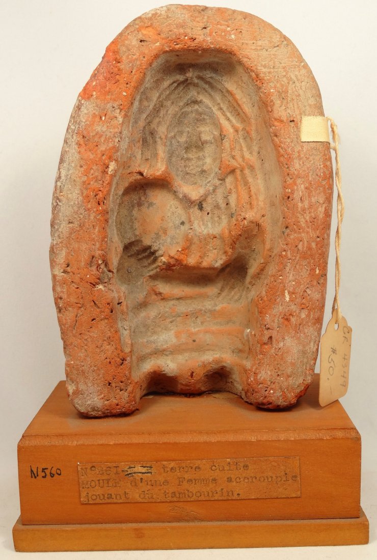 A Romano-Egyptian terracotta votive female mold: A Romano-Egyptian terracotta mold, c. 2nd-3rd Century AD, H: 5 1/4 in (13.4cm), W: 3 3/5 in (9.1cm), of a votive female with a tambourine. The piece has antique labels and collection number. A descrip