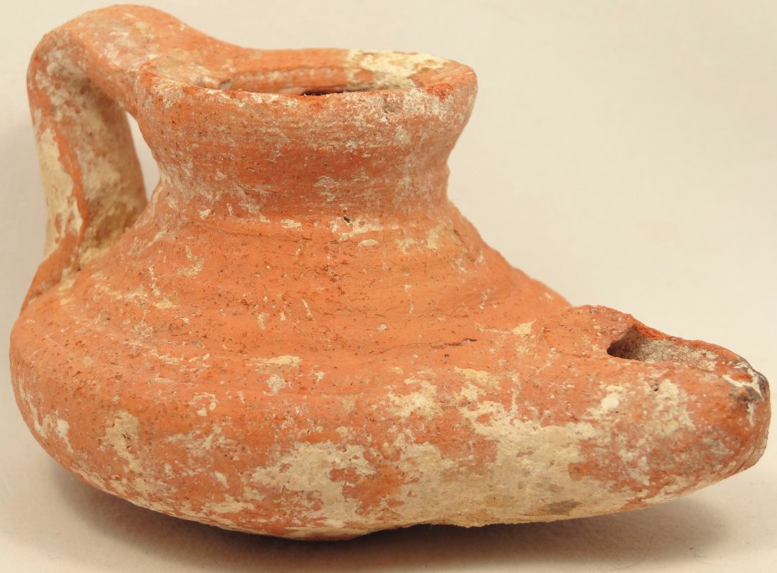 Islamic terracotta lamp of raised conical form: An Islamic terracotta lamp of raised conical form with ridged body, loop handle and protruding spout, 8th - 9th Century AD. H: 1.8 in(4.5cm), L: 3.3 in(8.4cm). Ex Maryland Private Collection.