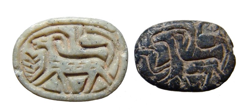 A pair of Egyptian 2nd Intermediate steatite scarabs: A pair of Egyptian 2nd Intermediate steatite scarabs, c. 1750 - 1570 BC, the first in a light grey-green steatite with nicely carved body and a horned goat on the base, palm before, (17 x 12mm), the s
