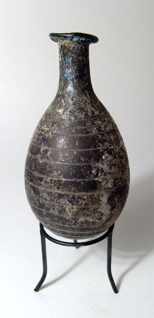 A Roman pale yellow glass ovoid bottle: A Roman pale yellow glass ovoid bottle, Eastern Mediterranean, c. 1st Century AD, with white spiral threading from the shoulder to the base. The body is ovoid with lightly flattened base, the neck tub