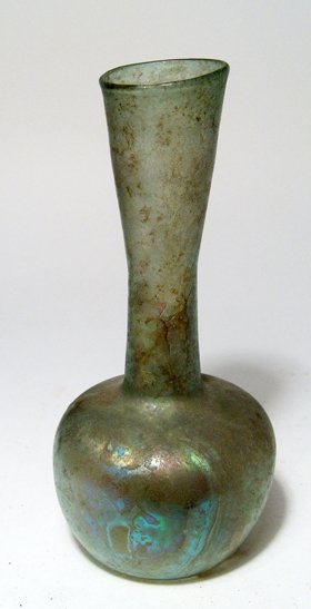 A tall pale green Roman glass bottle: A tall pale green Roman glass bottle, Eastern Mediterranean, c. 2nd - 3rd Century AD, the body round with indented base, the neck tubular with wide mouth. H: 6 1/4" (15.9 cm). Intact with areas of bea