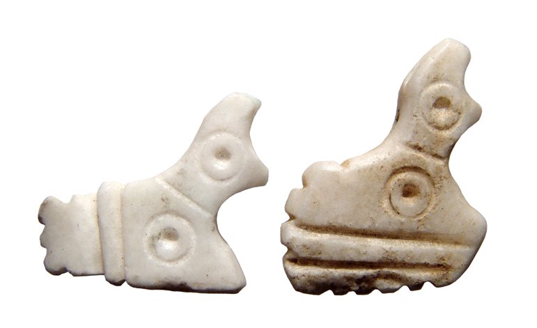 A pair of Sumerian alabaster amulets: A pair of Sumerian alabaster amulets, Jemdat Nasr Period, c. 3100 - 2900 BC, each in the form of a stylized recumbent goat and decorated with incised circles and lines, horizontal suspensions holes th