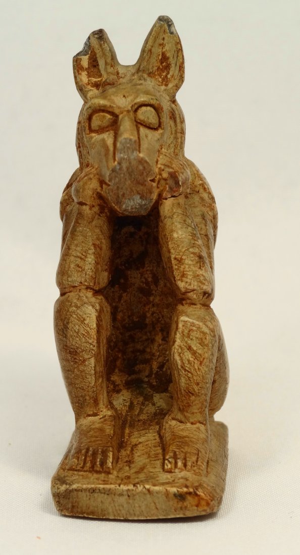 A steatite figure of the God Anubis: A steatite figure of the God Anubis, Late Period, c. 663-30 BC, depicted in a seated position with elbows on knees and hands to his face, wearing a cloak that covers his back and rear of head, H: 2 1/