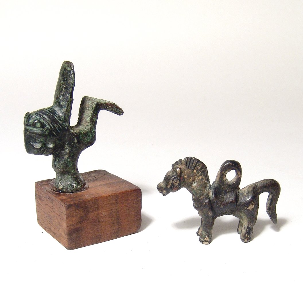 Roman casket leg & Central Asian horse: A Roman bronze casket leg and a Central Asian bronze horse. The bronze casket leg, Roman, c. 1st Century AD, adorned with the head of a lion. H: 2" (5.1 cm). On stand. The bronze horse, c. 1st Millenn