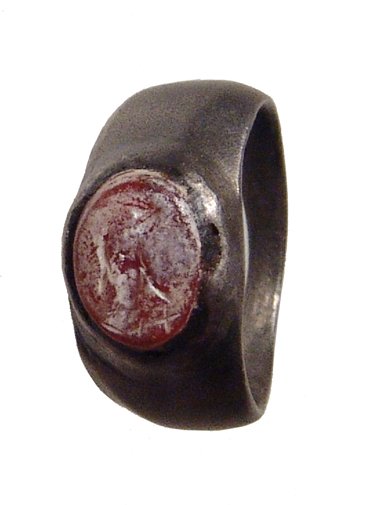 A Roman silver ring with intaglio: A Roman silver ring with intaglio, c. 1st Century AD, the carnelian ring stone with a Fortuna standing holding a rudder and cornucopia. Intact, the ring with even grey tone. W: 2.1 cm, ring size about
