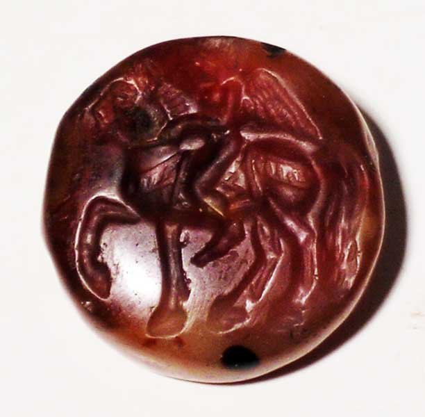 A choice Sasanian seal, c. AD 224 – 651: A choice Sasanian seal, c. AD 224 – 651. It depicts a superbly detailed Winged Cupid riding a horse. Carved from translucent carnelian and perforated laterally for suspension, D: 1 in (2.5cm). Expec