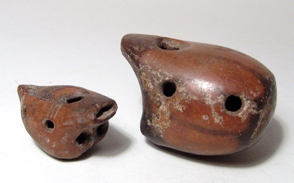 A pair of Colima ceramic whistles, West Mexico: A pair of Colima ceramic whistles, West Mexico, c. 250 BC - AD 250, both with beautiful orange burnished surfaces with areas of black throughout, the smaller with neatly incised geometric decoration. 