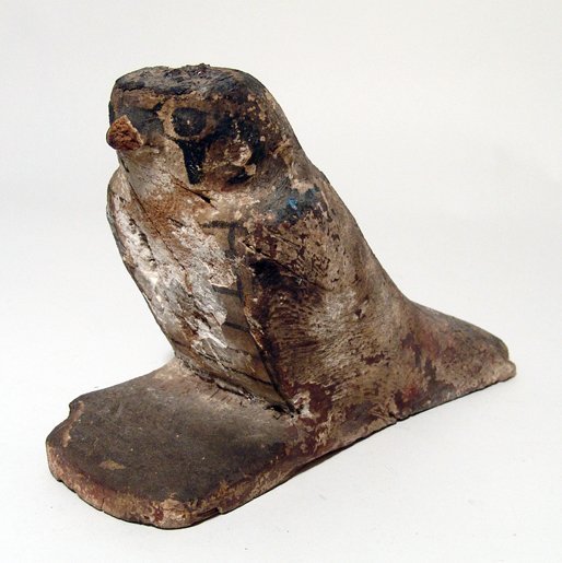 Egyptian wooden falcon, Late Period: An Egyptian wooden falcon, Late Period, c. 664 - 30 BC, perhaps the falcon god, Sopdu, from the lid of an ushabti box. Remains of paint on face and collar. L: 7 1/4" (18.4 cm). Some weathering and los