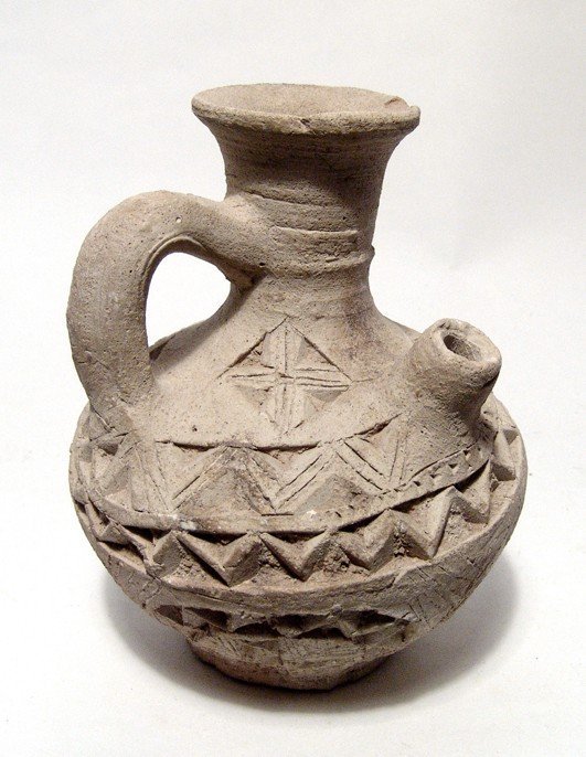 Central Asian creme jug with decoration: A nice Central Asian creme buff jug with deeply incised decoration, ca. 9th - 11th Century AD, with a single handle, tall necked mouth and a small spout. Intact and interesting. H: 5 3/8" (13.7 cm). E