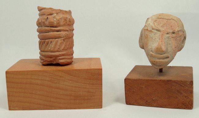 A lot of 2 Pre-Columbian terracottas: A lot of 2 Pre-Columbian terracottas. The first a Vera Cruz head, 400-800 AD, with a flat face, stretched ears, and large nose and lips, H: 1 3/10 in (3.4 cm). The second piece is a partial roller wit