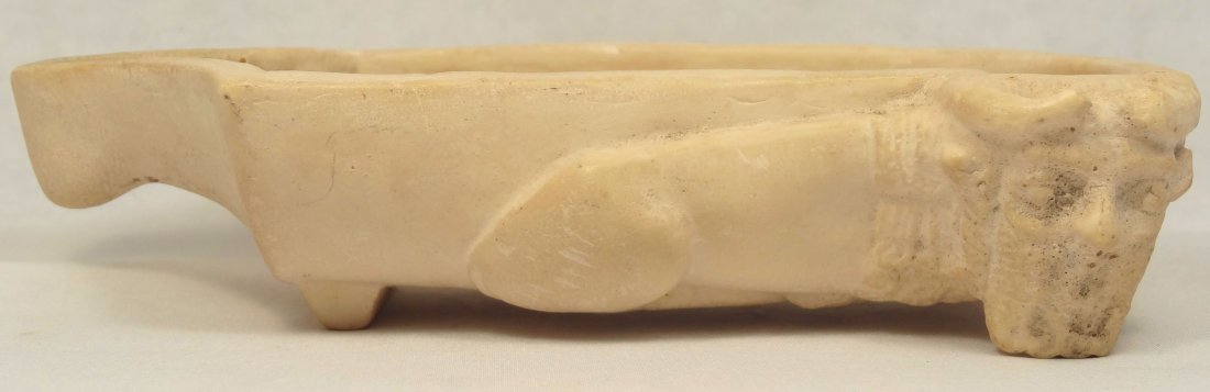 Museum copy of Syrian dish: A composite museum copy of a Syrian footed dish, with one side decorated in relief with a recumbent human headed bull, L: 6 in (15.2cm), W: 3 1/8 in (8cm).