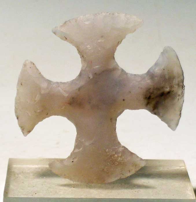 Maya eccentric from Guatemala: An exceptional Maya eccentric from Guatemala, c. 250 – 600 AD. This classic version of a Kan cross is 2 ¼ in (5.7cm) wide and is made from translucent chalcedony. Beautifully flaked, areas of calci