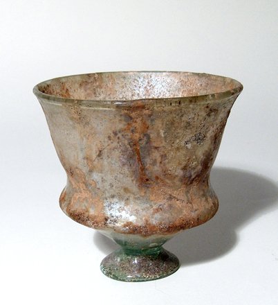 Large Roman green glass footed cup: A large Roman green glass footed cup, c. 3rd - 4th Century AD, the foot flared with narrow top, the cup with large ridge along the lower portion then flaring to a wide mouth. H: 4 in (10.2 cm); Dia: 3