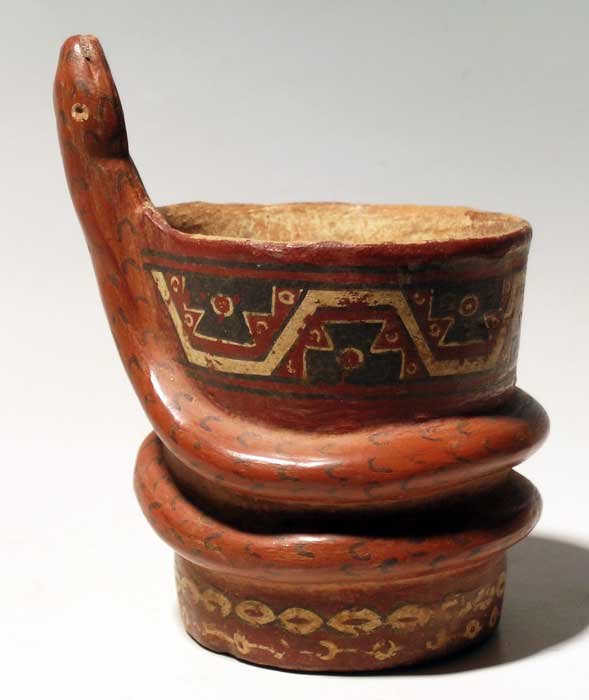 Intricate Inca serpent kero from Peru: An intricate Inca serpent kero from Peru, c. 1300 – 1500 AD. It is 4 ¾ in (12.1cm) high and is elaborately decorated with a register of water symbols at the top and connected ornament designs at th