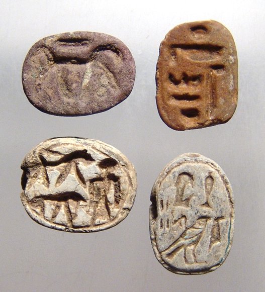 A lot of 4 Egyptian scarabs: Lot includes a pair of New Kingdom steatite examples, c. 1570 - 1075 BC, one Ramesside with the pharaoh before two lions, (17 x 13mm), and the other with neatly incised hieroglyphic characters, (17 x 