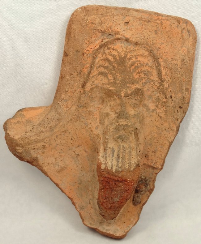 Roman terracotta pot-support: A Roman terracotta pot-support, Ptolemaic Period, late 3rd - mid-1st Century BC, with a mask of Papposilenos, with long striated beard within a rectangular panel, H: 5 1/3 in (13.5 cm), W: 3 7/8 in (9