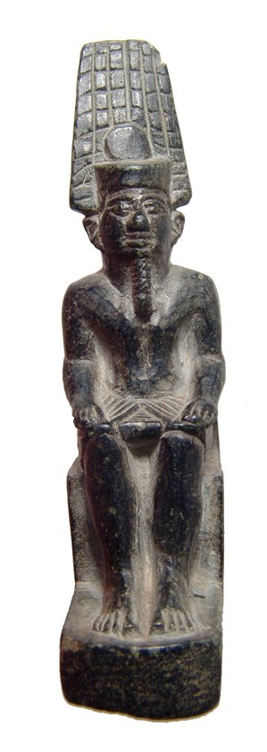 Egyptian black serpentine figure of Amun Re: An Egyptian black serpentine figure of Amun Re, Late New Kingdom, c. 1200 - 1075 BC, the god of Thebes is depicted seated on a throne, plinth at back with suspension hole behind neck, wearing feathere