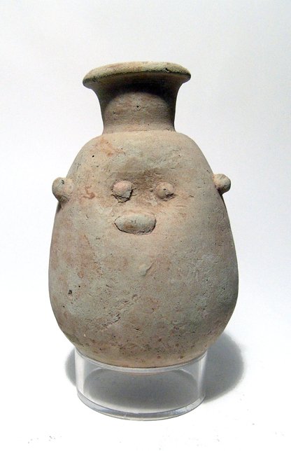 An Egyptian ceramic Bes jar: An Egyptian ceramic Bes jar, Late Period, c. 664 - 343 BC, ovoid in shape with rounded bottom, the neck tubular with flared mouth. The side of the vessel is indented with added eyes, nose and ears, th