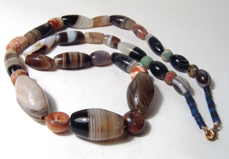 Necklace composed of Near Eastern banded-agate beads: A large necklace composed of Near Eastern banded-agate beads, c. 1st Millennium BC, mostly of the tubular type with tapered ends many with an ‘eye’ pattern on the side. The banded agate beads are