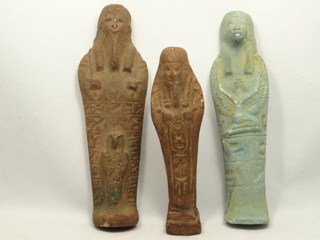 A collection of 3 Egyptian-style ushabtis: A collection of 3 Egyptian-style ushabtis, 19th Century AD. The first a brown faience ushabti wearing tripartite headdress with crossed arms and hands holding hoes. The front is inscribed with hierogl