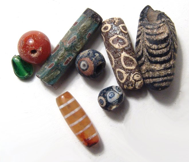 A lot of 8 Islamic glass and stone beads: A lot of 8 Islamic glass and stone beads, c. 7th - 15th Century AD, all attractive, the carnelian etched bead quite nice! Largest measures 3 cm in length. Ex Los Angeles private collection.