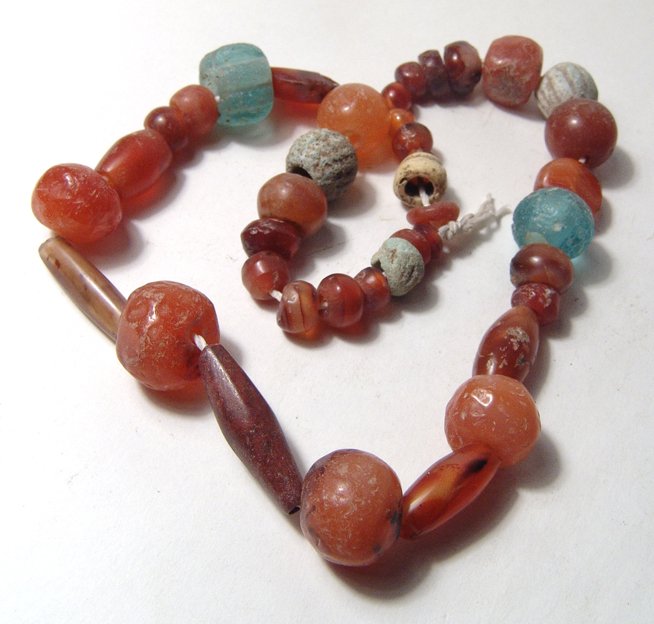 Near Eastern Carnelian and Glass beads: A strand of Near Eastern Carnelian and Glass beads. The carnelian beads are of varying sizes and shapes, c. 1st Millennium BC, with good polish, and includes a long jasper bead of roughly the same per