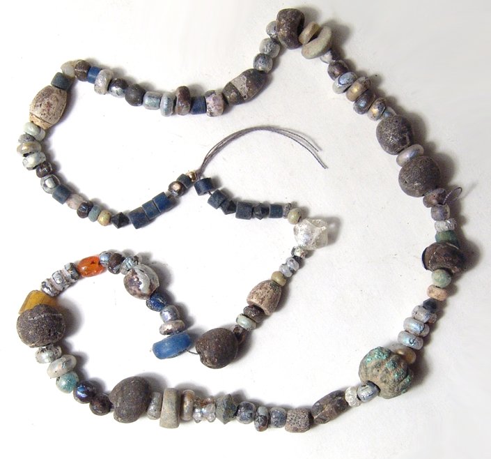 A strand of mixed ancient beads from the Levante: A strand of mixed ancient beads from the Levante, mostly Roman glass types but also much older lapis tubular beads, a few odd stone disk and wedge-shaped beads and a large lobed bronze bead. A nice mi