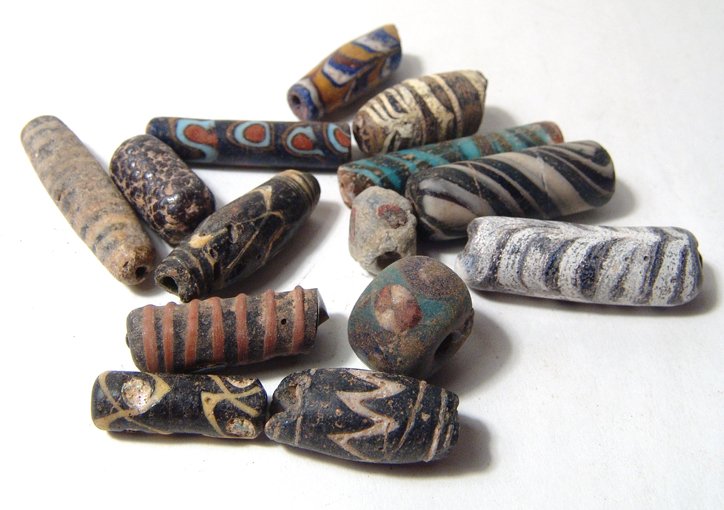 14 Byzantine and Islamic glass beads from the Holy Land: A group of 14 Byzantine and Islamic glass beads from the Holy Land, c. 7th - 10th Century AD, of various sizes and shapes, all with vivid color. Largest bead measures 4 cm in length. A few with minor 